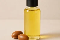 Argan oil in a clear glass bottle with argan nuts to the side