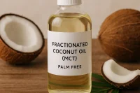 A bottle of fractionated coconut oil with coconuts around it