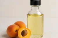 A bottle of light coloured apricot kernel oil with apricots to the side