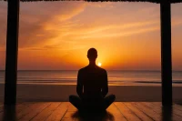 Man meditating overlooking the ocean at sunrise