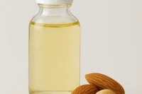 Refined almond oil in a clear bottle with almonds at its base