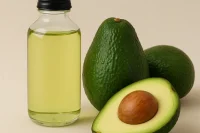 Avocado oil in a glass bottle with avocados to the side
