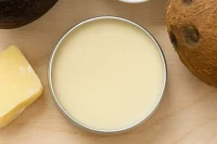 Tin of lip balm surrounded by ingredient components