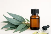 Eucalyptus blue gum essential oil in a dish and dropper with amber bottle and eucalyptus leaves