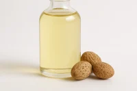 Clear glass bottle of golden Mongongo Nut Oil with three Mongongo nuts on a white background.