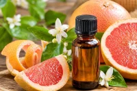 Pink grapefuit surrounding amber essential oil bottle