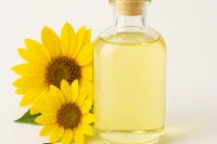 Clear glass bottle of pale yellow Organic Refined Sunflower Oil with bright sunflowers and sunflower seeds on a white background.